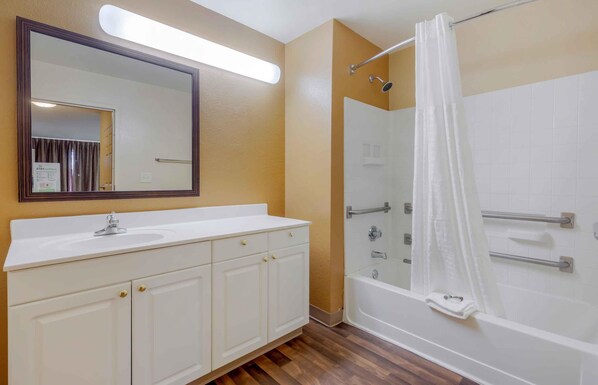 A bathroom with a white vanity, a large mirror, a shower with a glass door, and a white bathtub.