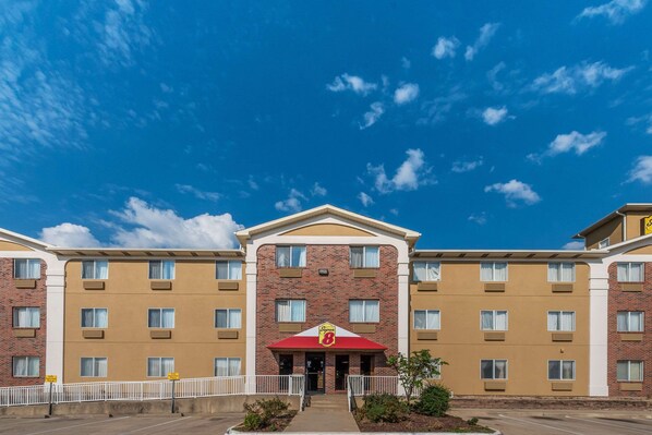 A hotel with a brick facade, multiple windows, and a central entrance with a red awning. - Super 8 by Wyndham Denton (Denton)