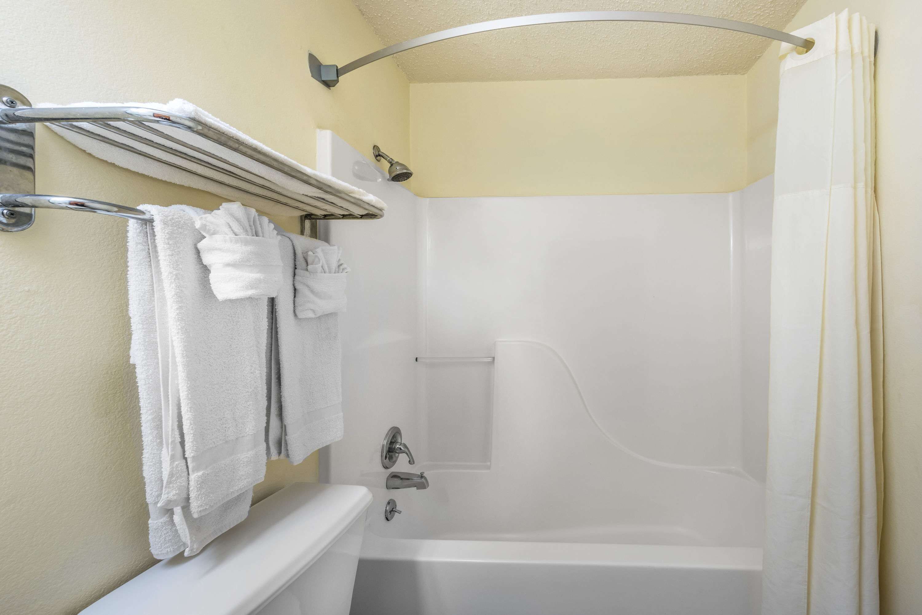 A bathroom with a bathtub, a shower, and a towel rack with towels.