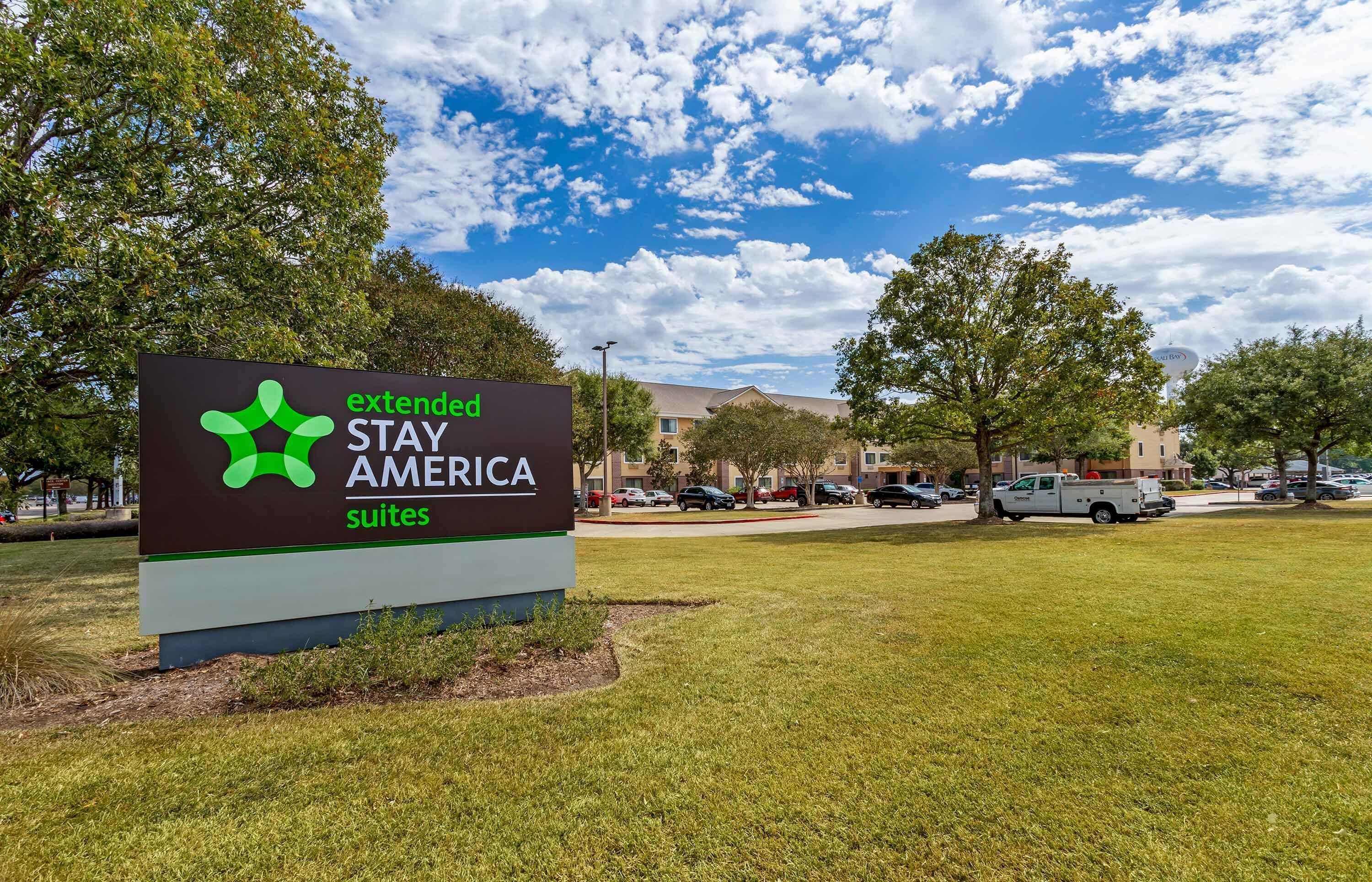 Schild für Extended Stay America Suites mit blauem Himmel und Bäumen im Hintergrund.