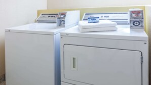 Zwei weiße Waschmaschinen mit Frontlader, einer Bedienblende und eine Packung Purex Waschmittel darauf.