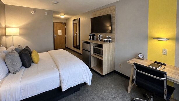 Ein Hotelzimmer mit einem Bett, einem Schreibtisch, einem Spiegel, einem Fernseher und einer Mikrowelle.