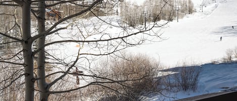 A snowy mountain landscape with bare trees and a ski lift.