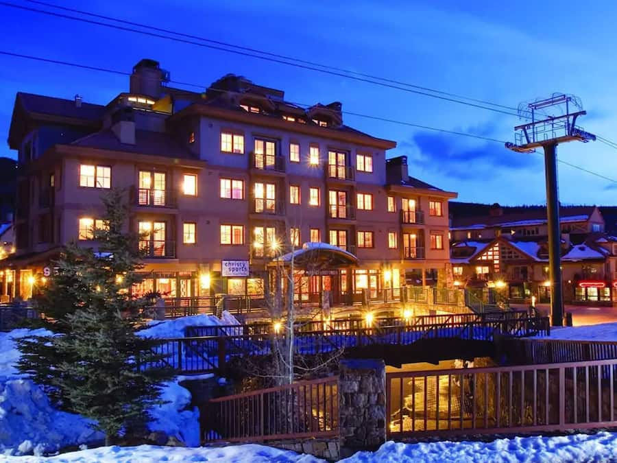 A multi-story hotel with illuminated windows and a snow-covered ground.