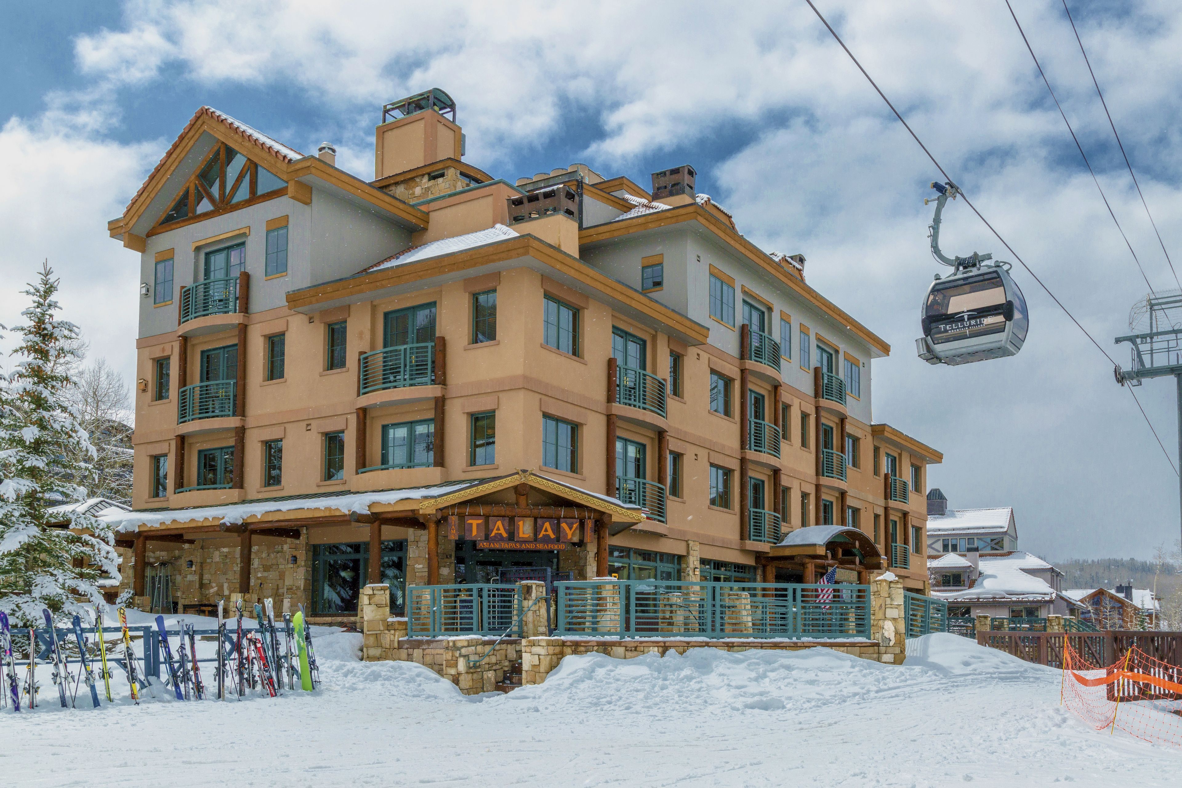 A multi-story hotel with a ski lift in the background.
