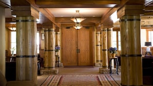 Un pasillo con columnas de madera, una puerta grande de madera y lámparas colgantes.