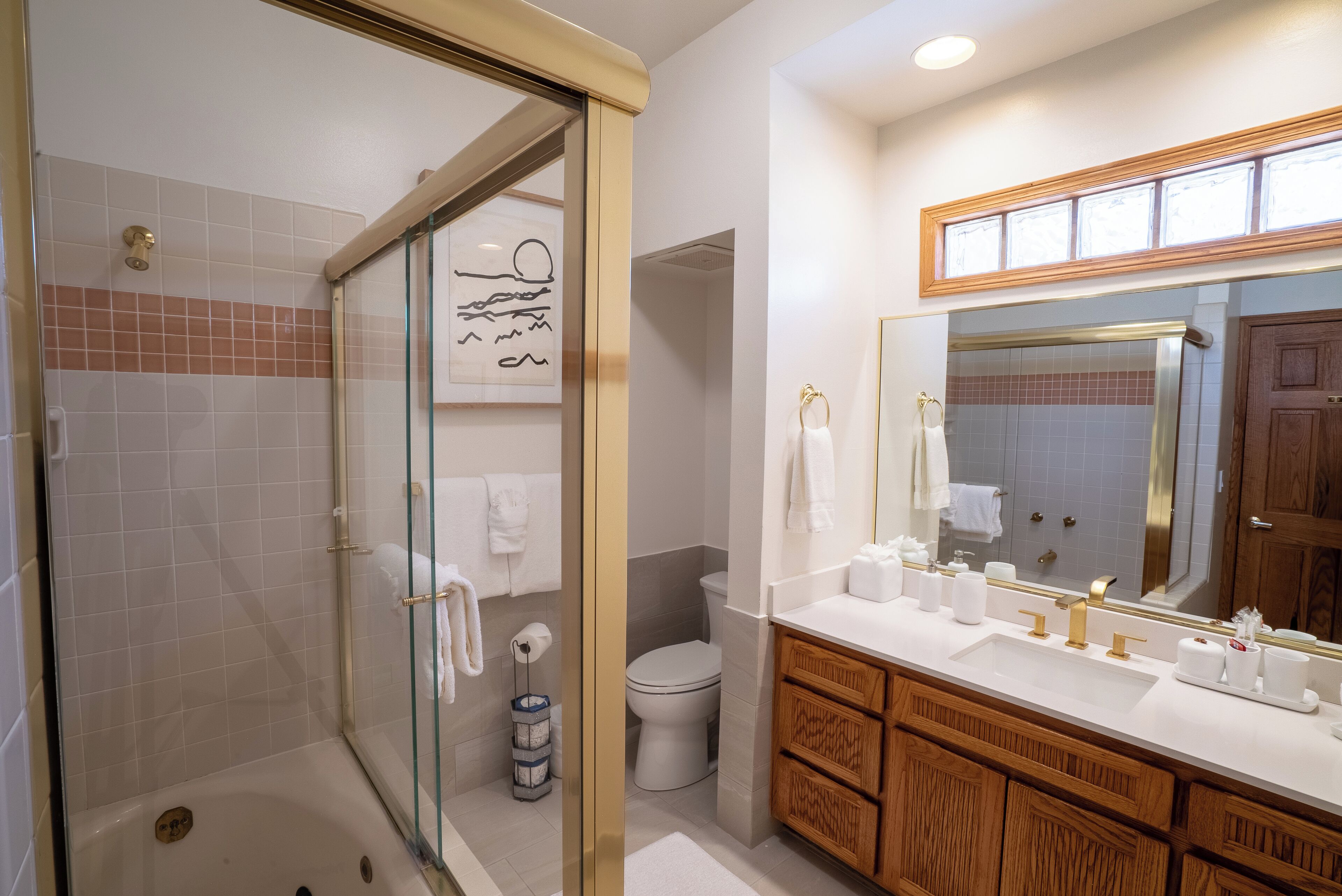 A modern bathroom with a glass shower enclosure, a white toilet, and wooden cabinetry.