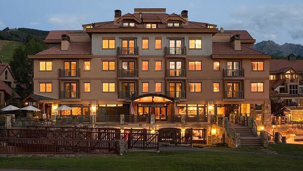 Un hotel de varios pisos con entrada central, balcones y una fachada bien iluminada.