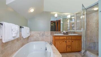 Un baño moderno con una bañera grande, tocador de madera y cabina de ducha de vidrio.