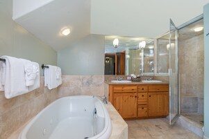 Un baño moderno con una bañera grande, tocador de madera y cabina de ducha de vidrio.