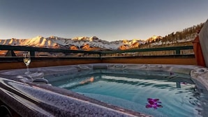 Un jacuzzi con vistas despejadas a montañas nevadas al fondo.