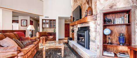 A spacious living room with a fireplace, comfortable seating, and a bookshelf.