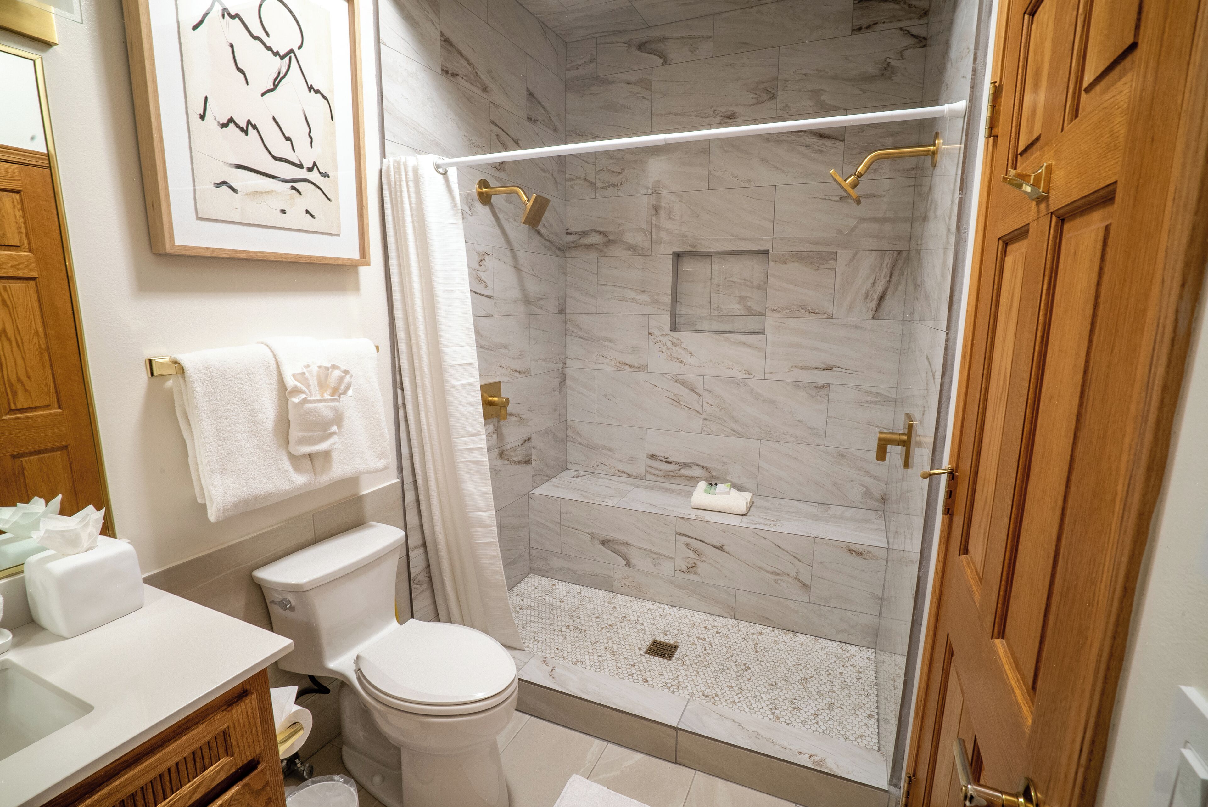 A bathroom with a shower, toilet, sink, and a towel rack.