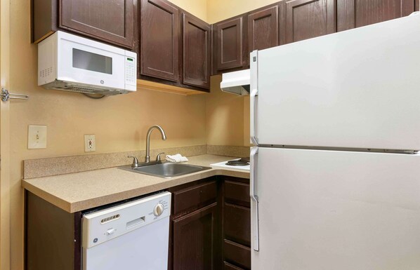 Una cocina compacta equipada con microondas, fregadero, lavavajillas y refrigerador.