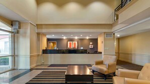 A hotel lobby with a reception desk, a striped carpet, and leather armchairs.