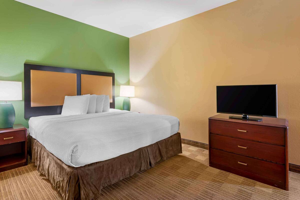 Ein Hotelzimmer mit Bett, Fernseher und Kommode.