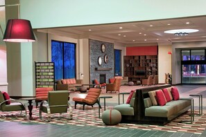 A spacious lobby with a seating area, a fireplace, and a collection of decorative plates. - Four Points by Sheraton Bentonville (Bentonville)