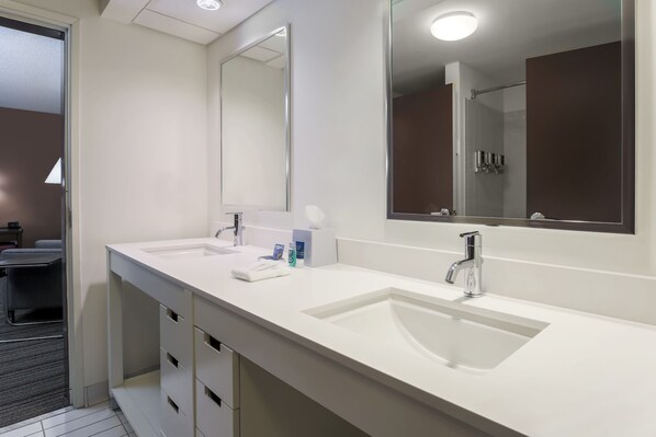 Un baño moderno con dos lavamanos, un espejo grande y una zona de ducha.