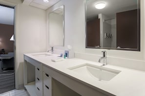 A modern bathroom with two sinks, a large mirror, and a shower area.
