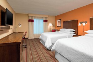 A hotel room with a wooden desk, two beds, a TV, and a window with curtains. - Four Points by Sheraton Bentonville (Bentonville)