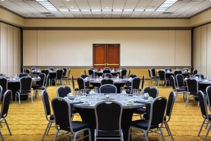 Un salón de conferencias con varias mesas redondas, cada una dispuesta con sillas, vasos y cubiertos.