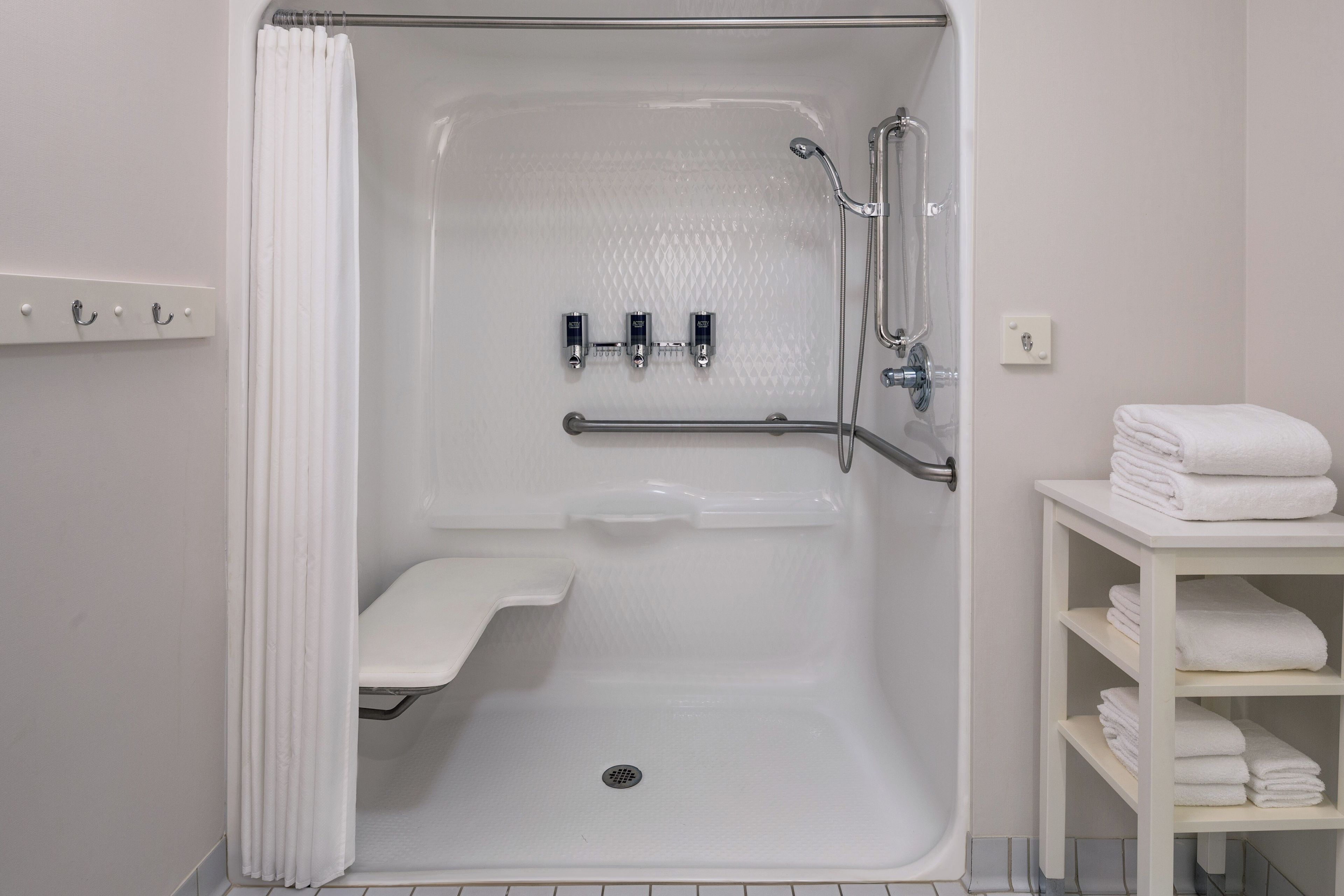 Een inloopdouche met een vloer van witte tegels en een handdouche.