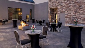 Un patio al aire libre con mesas y sillas redondas, una chimenea y una pared de piedra.