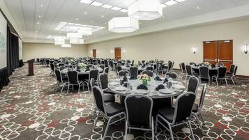 Une salle de conférence avec des tables rondes, des chaises noires et un tapis à motifs.