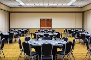 Un salón de conferencias con varias mesas redondas, cada una dispuesta con sillas, vasos y cubiertos.