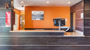 A hotel reception area with a modern design, featuring a reception desk, a clock, and a sign for 'Econotodge by Choice Hotels'.