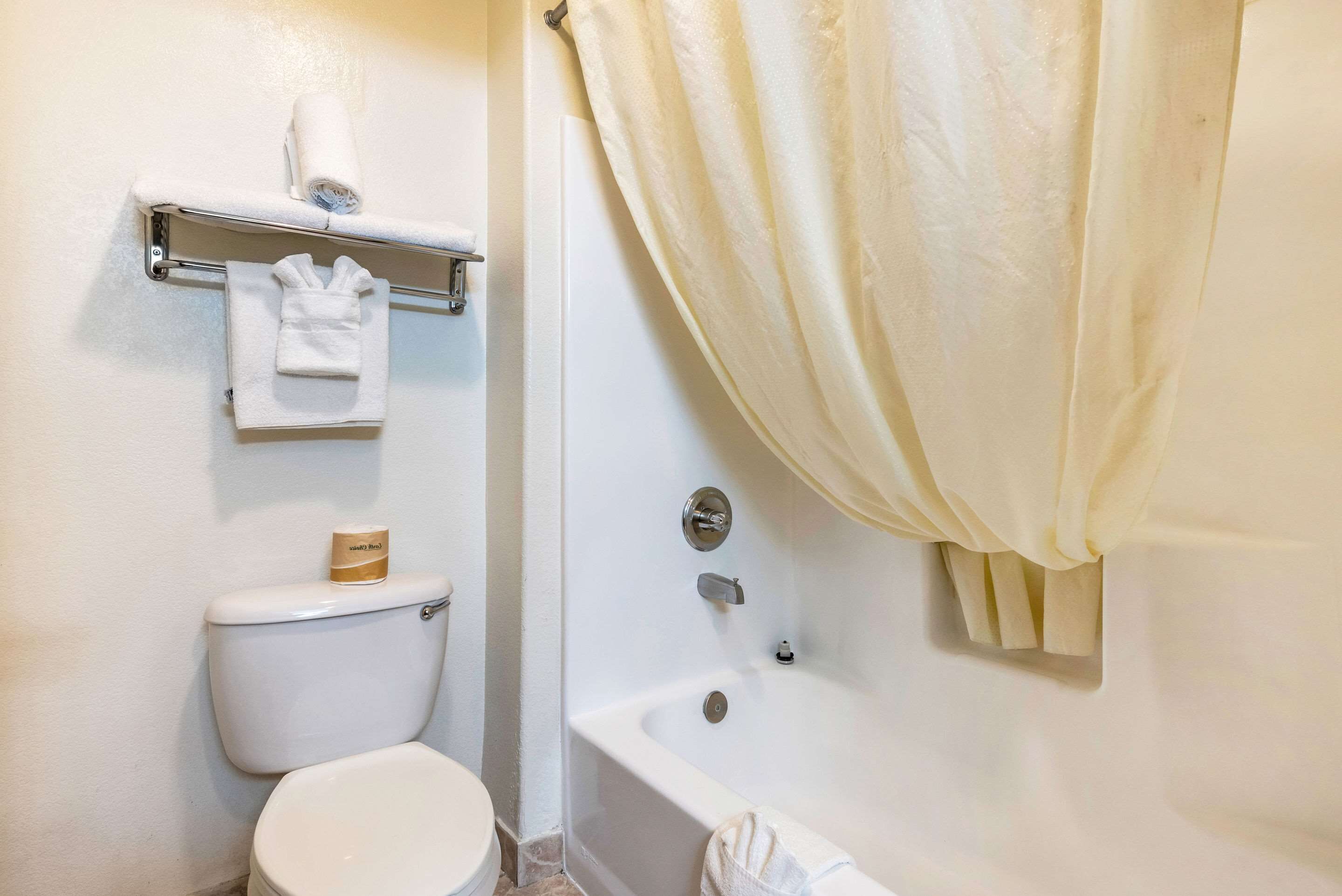 A bathroom with a toilet, a bathtub, a towel rack, and a shower curtain.
