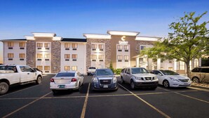 A hotel with a parking lot, multiple cars, and a building with a sign that reads "Comfort Inn Express." - Comfort Inn & Suites Pueblo (Pueblo)