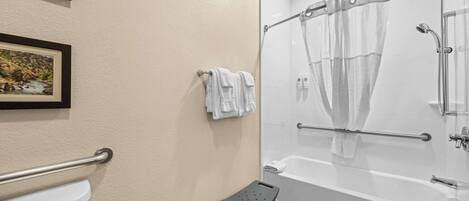 A bathroom with a bathtub, a shower, a toilet, and a small stool.