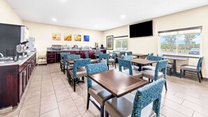 A restaurant with a kitchen area, dining tables, and chairs. - Comfort Inn & Suites Pueblo (Pueblo)