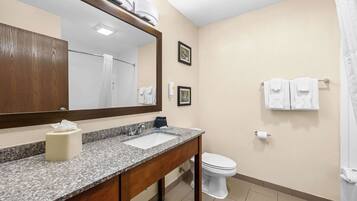 A bathroom with a granite countertop, a white sink, a mirror, a toilet, and a shower curtain.