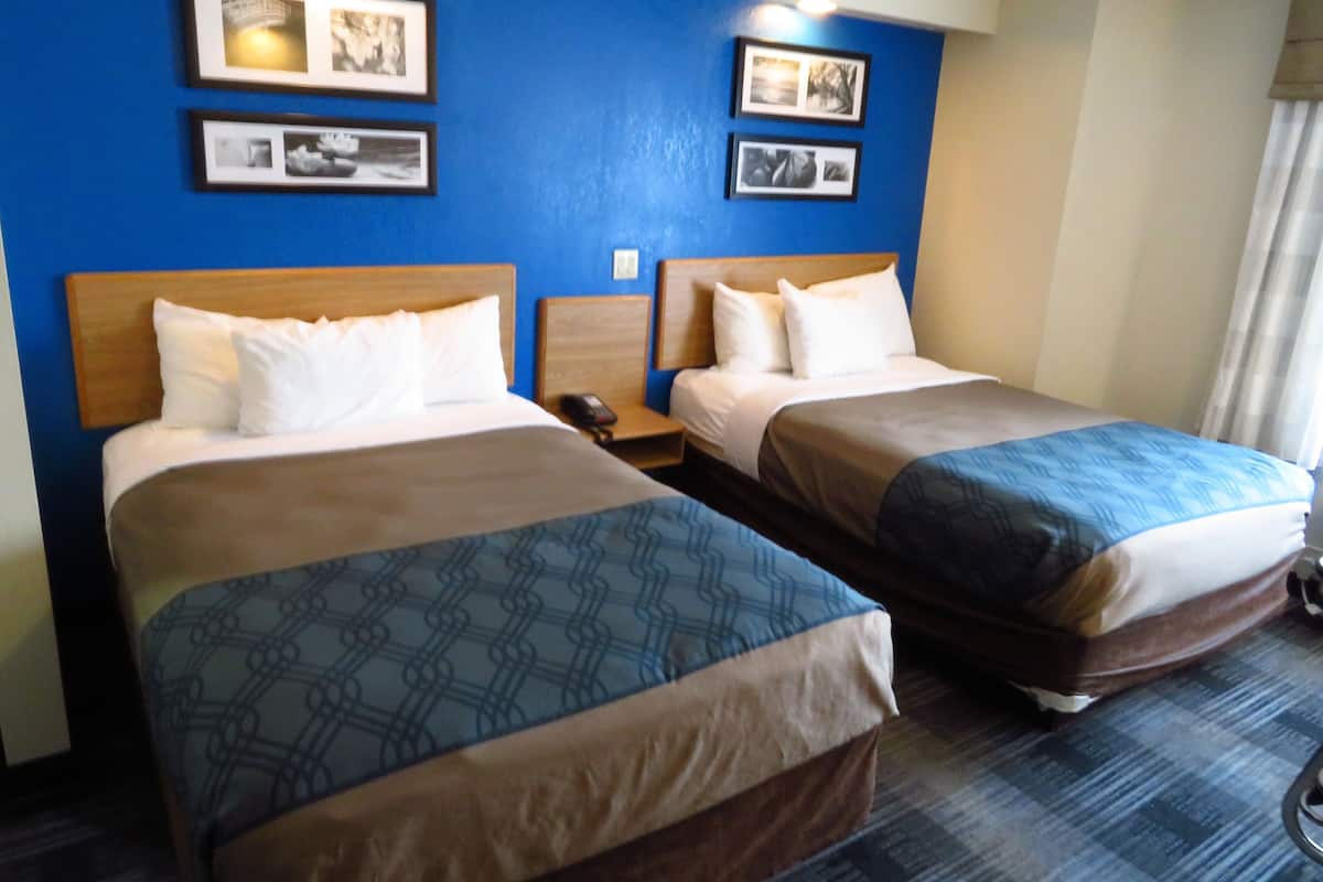 Two adjacent beds with headboards, a nightstand, and framed pictures on the wall.