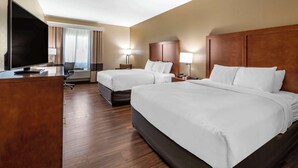 Une chambre d’hôtel avec deux lits, un bureau équipé d’un téléviseur à écran plat, d’un ordinateur portable et d’une chaise.