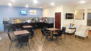 A breakfast area with a counter, seating, and a TV screen. - Days Inn by Wyndham Walcott Davenport (Walcott)