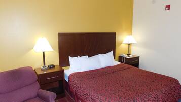 A hotel room with a bed, two bedside lamps, a telephone, and a chair.