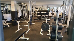 Une salle de sport équipée de divers appareils d’entraînement, notamment des machines de musculation, des haltères et des barres.