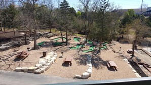 Un parcours de mini-golf avec plusieurs trous, des bancs en bois et un chemin de gravier.