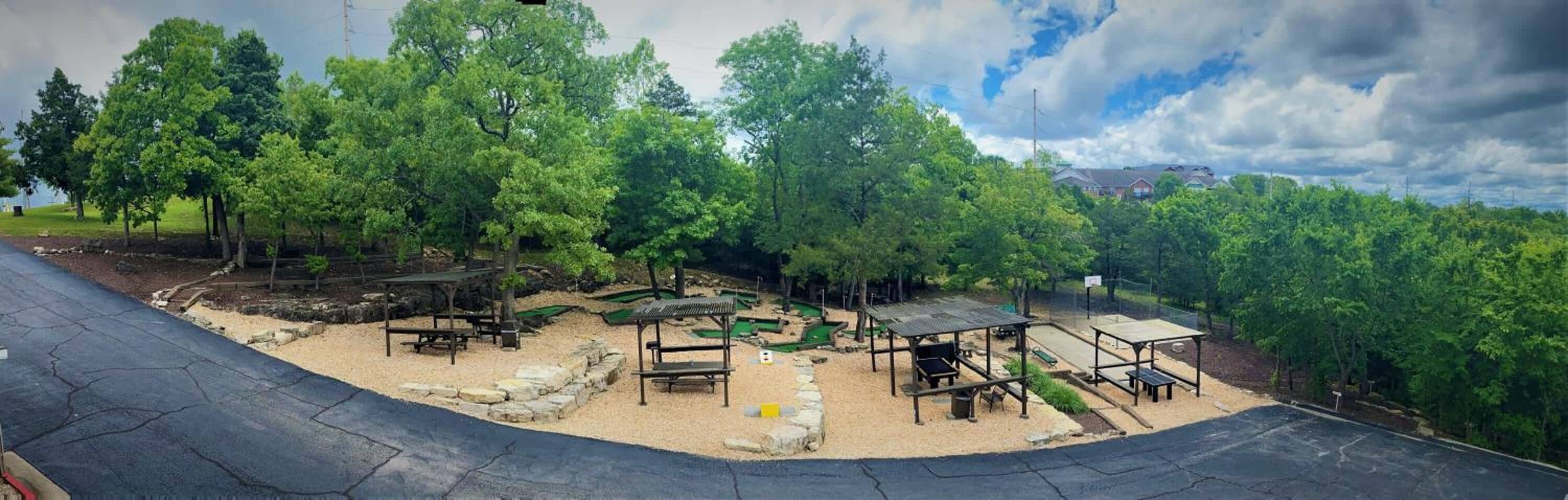 A park with picnic tables, a small green space, and a curved pathway.