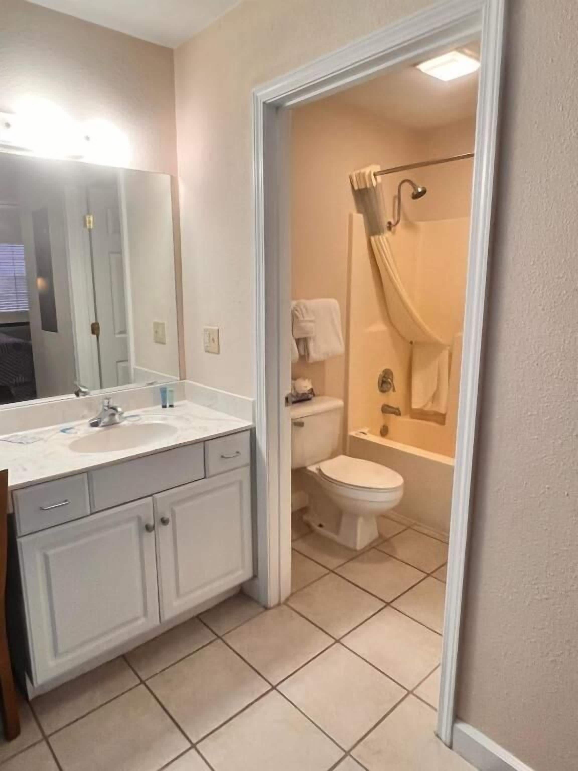 A bathroom with a toilet, shower, and sink.
