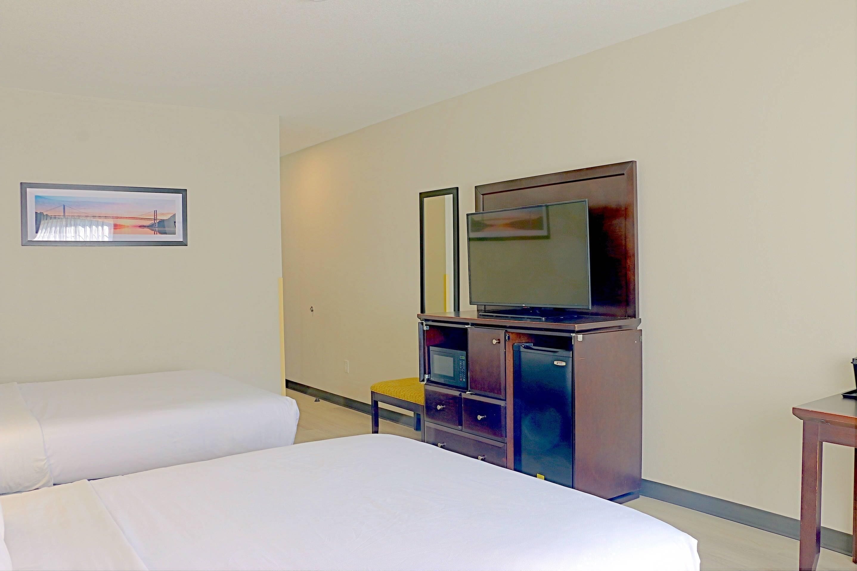 Habitación de hotel con dos camas, televisión, microondas y una mesita.