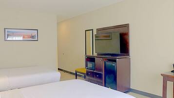 Habitación de hotel con dos camas, televisión, microondas y una mesita.