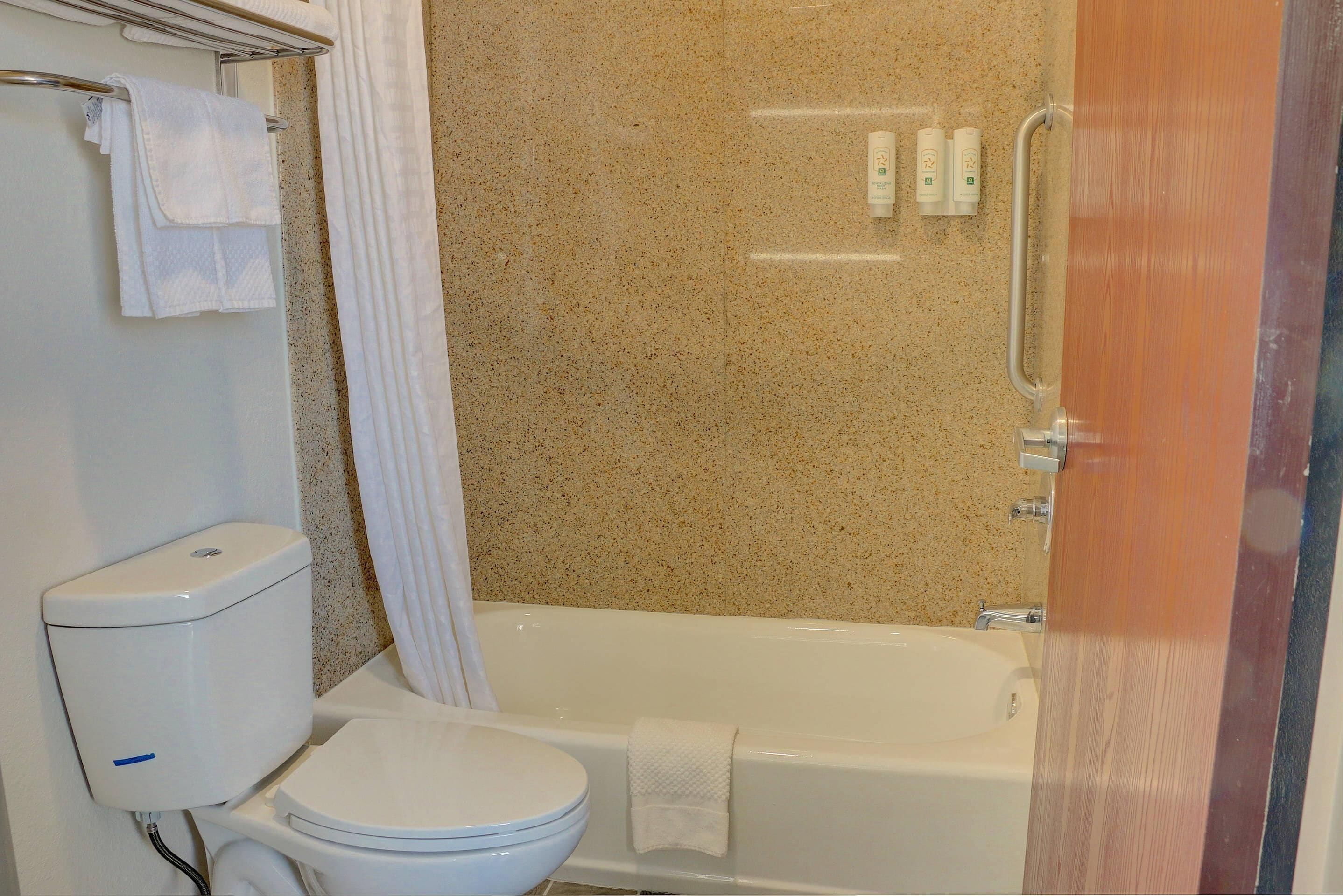 A bathroom with a toilet, bathtub, and shower curtain.