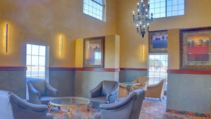 A lobby with leather armchairs, a glass coffee table, and framed artwork on the walls. - Quality Inn & Suites Roswell North (Roswell)