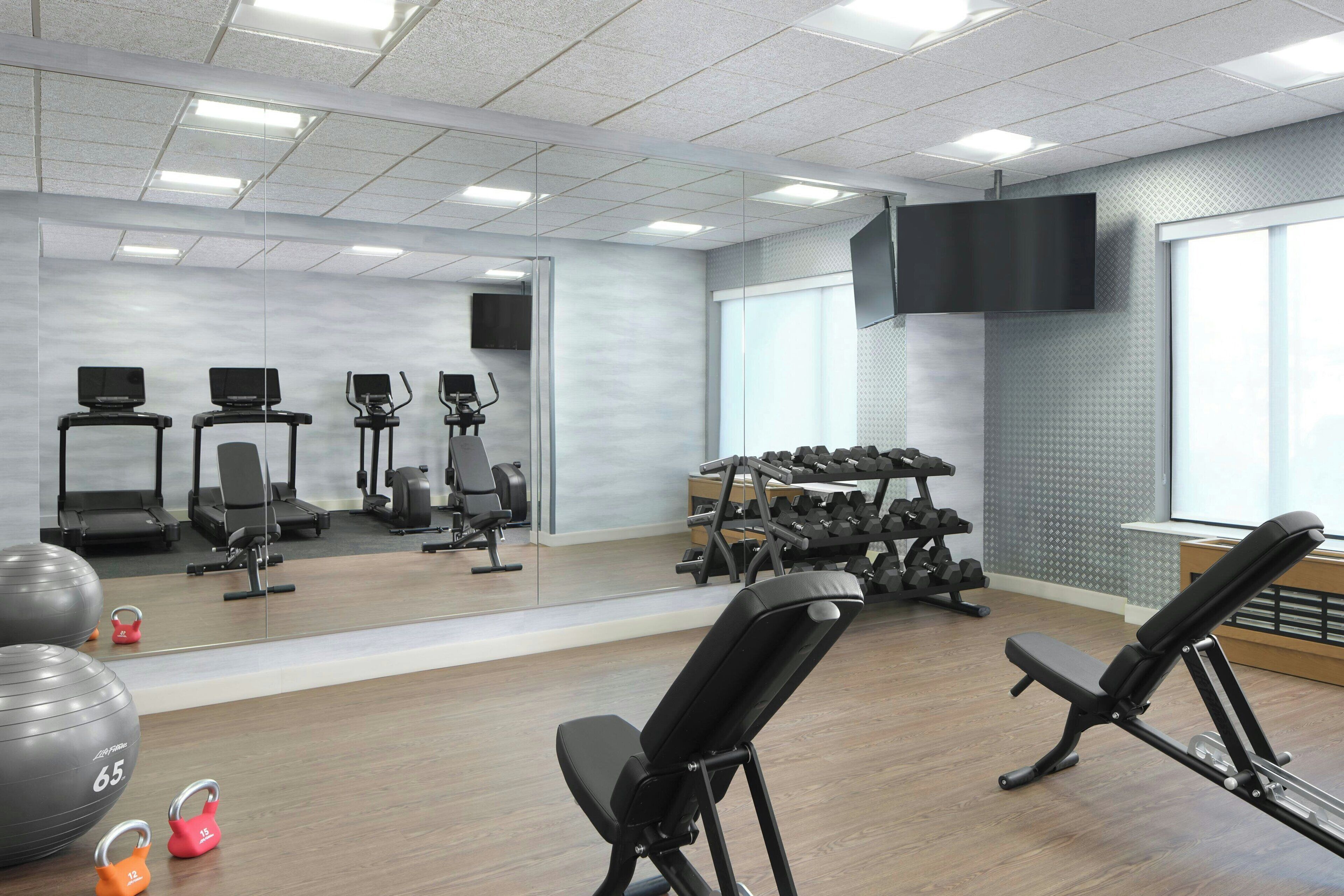 A gym with exercise equipment, a large mirror, and a television.