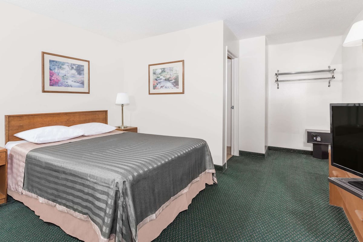 Habitación de hotel con cama, televisión, escritorio y dos cuadros en la pared.