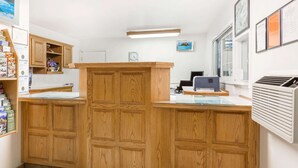 A reception area with wooden cabinets, a reception desk, a computer, and framed certificates on the wall.